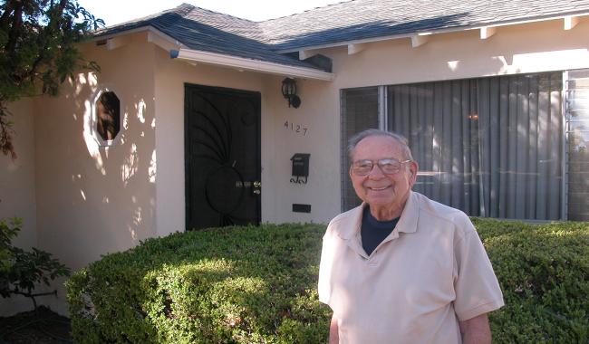 A proud senior standing in front of his home after receiving Handyworker services.