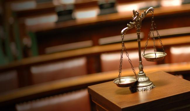 scale of justice leaning to the left int a court room
