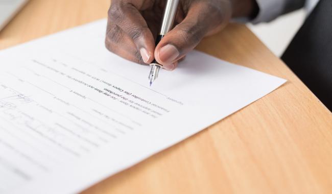 An image of a person writing on white paper