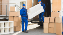 Two movers lifting a couch into a moving van.